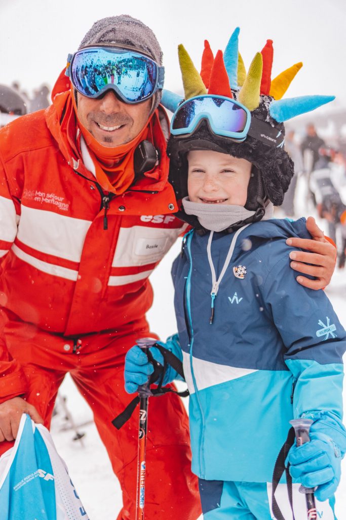Photo d'un enfant avec un moniteur de ski qui lui donne sa médaille flocon